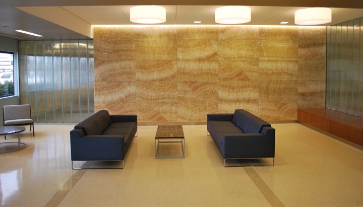 Lobby lounge with a warm stone feature wall and light porcelain floor