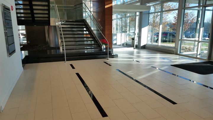 Lobby staircase with dark linear inlays running through a light tile floor
