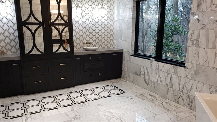 Marble bathroom with a patterned mosaic floor border and dark vanity