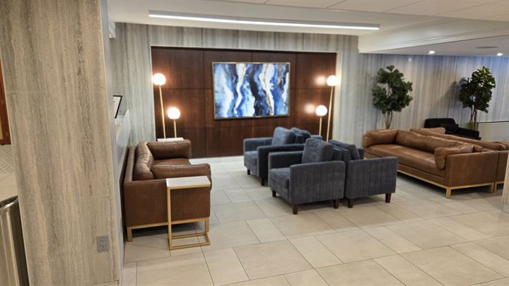 Lobby lounge with a large-format tile floor and walls clad in Laminam porcelain panels around a dark wood feature panel