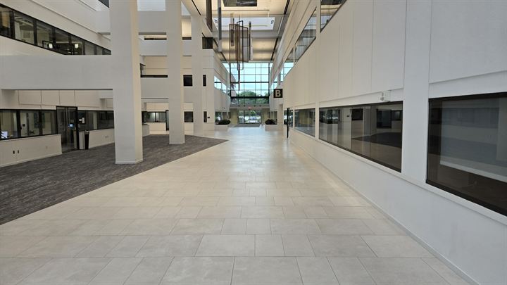 Long atrium corridor with light large-format porcelain floor tile