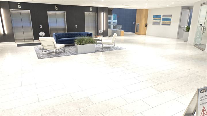 Elevator lobby with light large-format floor tile and a seating area