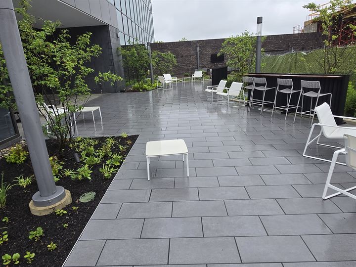Outdoor courtyard paved with large gray porcelain pavers around planting beds and a bar-height counter