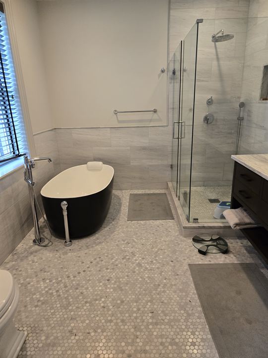 Bathroom with a hexagon marble mosaic floor, large-format marble walls and a glass shower